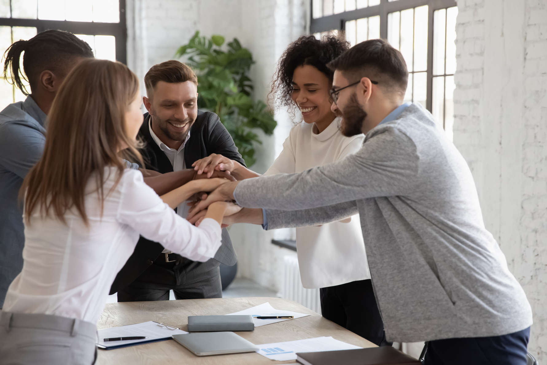 Successful diverse employees stacking hands, engaged in team building